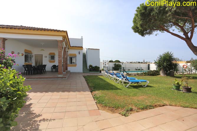 Vista del chalet con las tumbonas del jardin.