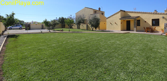 La casa tiene porche y frente a él hay una gran extensión de jardin.