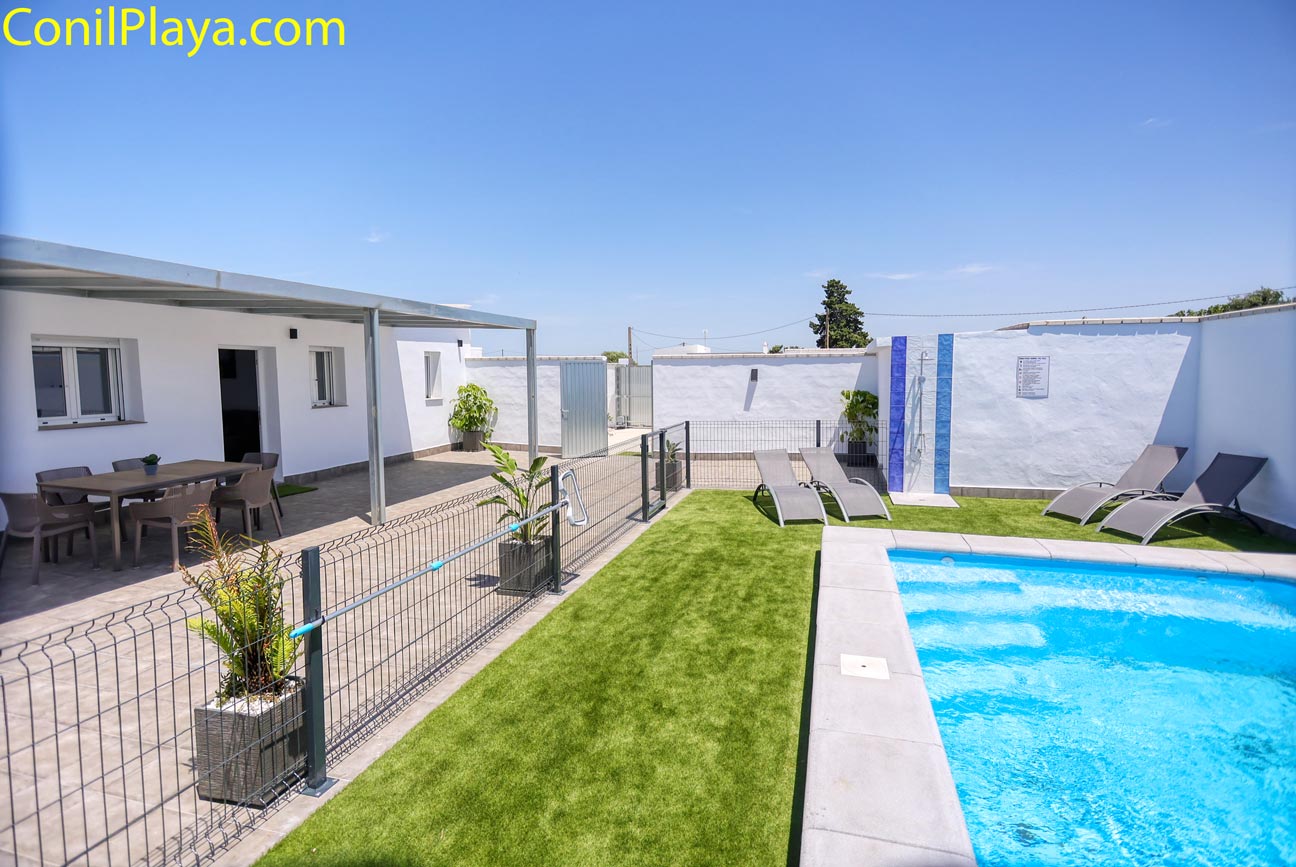 Zona exterior con piscina privada, césped y tumbonas junto a vivienda blanca