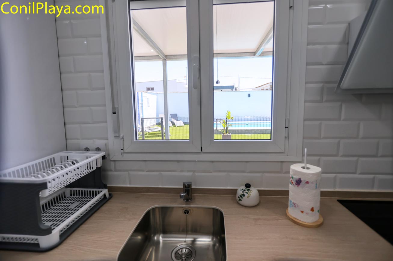 Fregadero de cocina con ventana que da a piscina y jardín privado