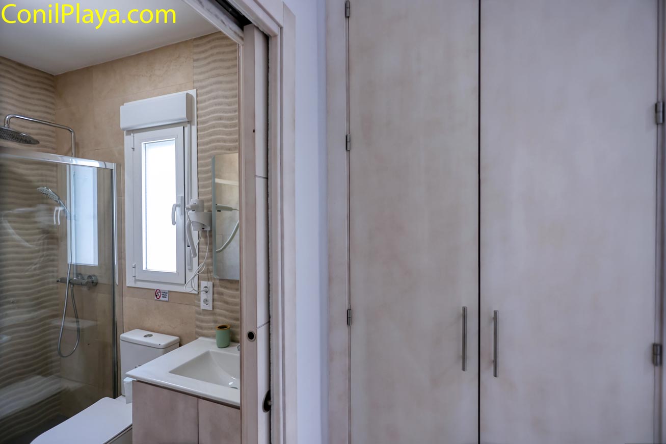 Cuarto de baño moderno con ducha y armario vistos desde el pasillo