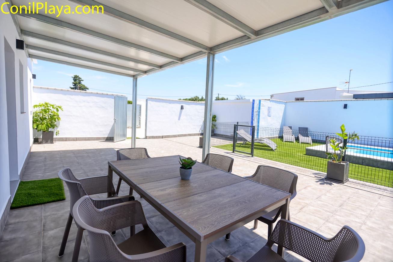 Mesa grande de comedor en el porche con vistas a piscina y jardín privado