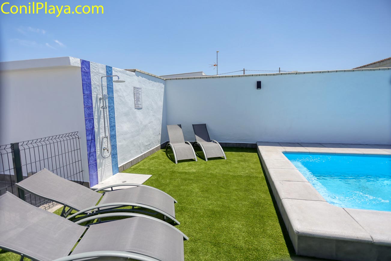 Zona exterior con piscina privada y varias tumbonas junto a pared blanca