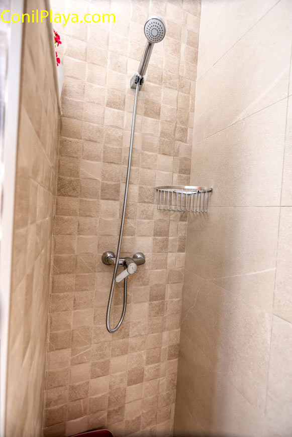 Ducha con azulejos beige y grifo cromado en cuarto de baño pequeño