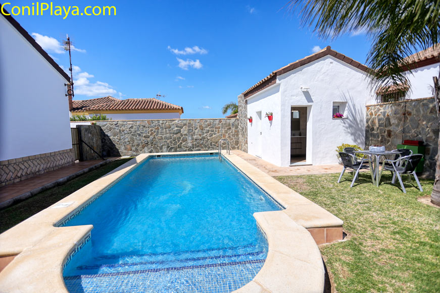 Piscina rectangular con escalones junto a jardín y paredes de piedra
