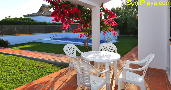 Porche con mesa y sillas frente a la piscina