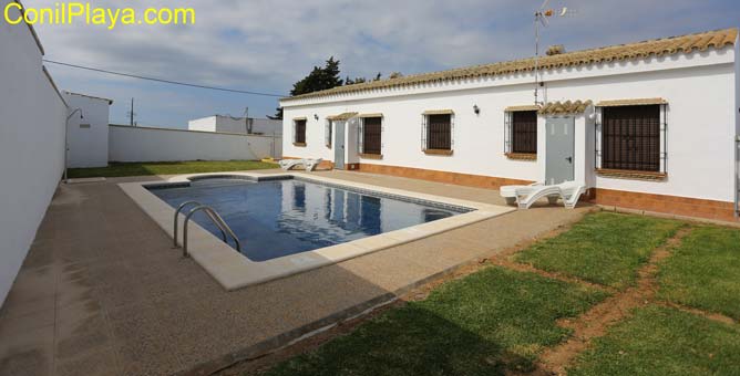 Jardín con césped junto a la piscina