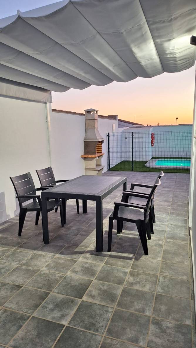 toldo con mesa y sillas junto a la barbacoa