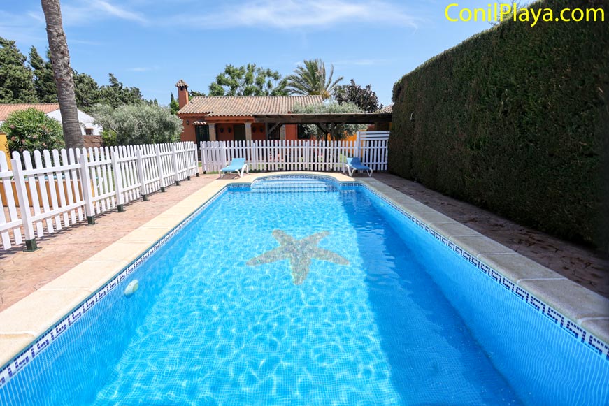 Piscina vallada con la casa vista desde el borde del agua