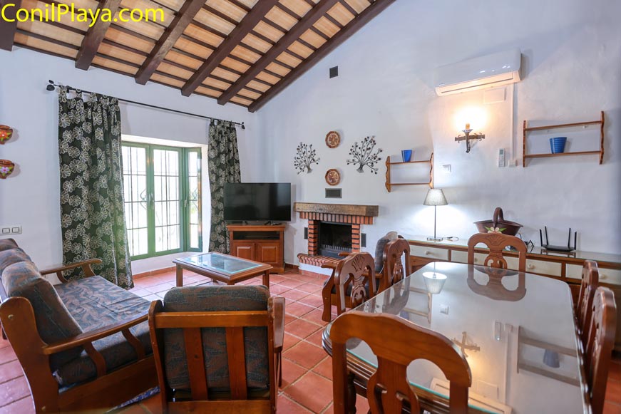 Salón con chimenea, sofá y mesa de comedor visto desde la entrada