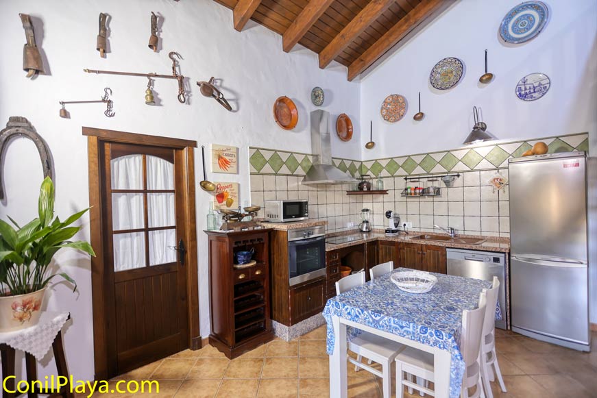 Cocina rústica con mesa central y decoración tradicional, vista desde la entrada