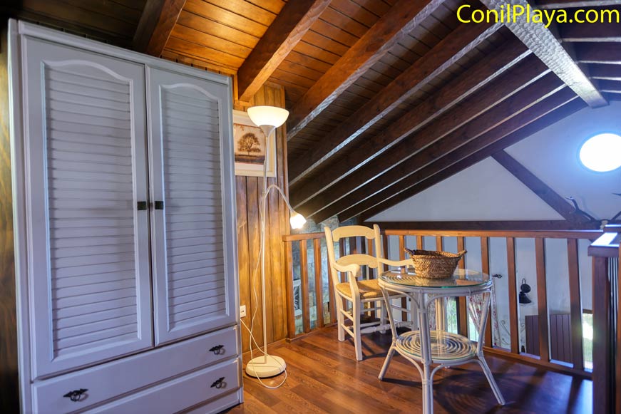 Dormitorio superior con armario y mesa pequeña de mimbre