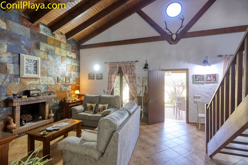 Salón amplio con chimenea, sofás y techo de vigas visto desde la entrada