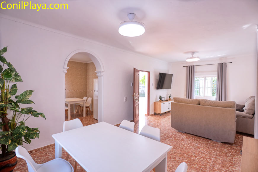 Vista interior de un salón con sofá y mesa comedor blanca
