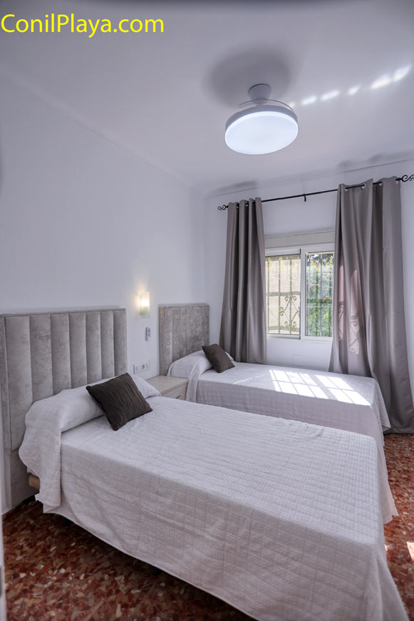Dormitorio con dos camas individuales, ventana y ventilador de techo moderno