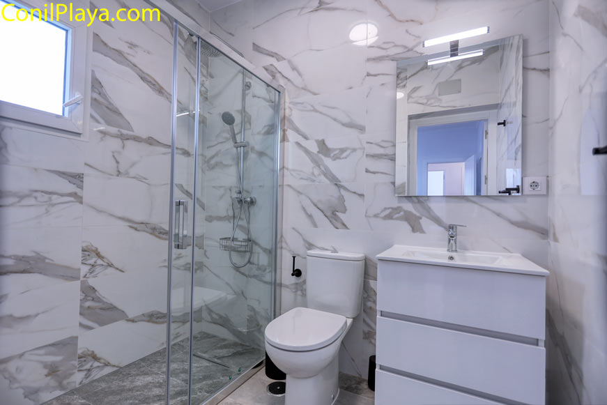 Cuarto de baño moderno con ducha mampara visto desde la entrada