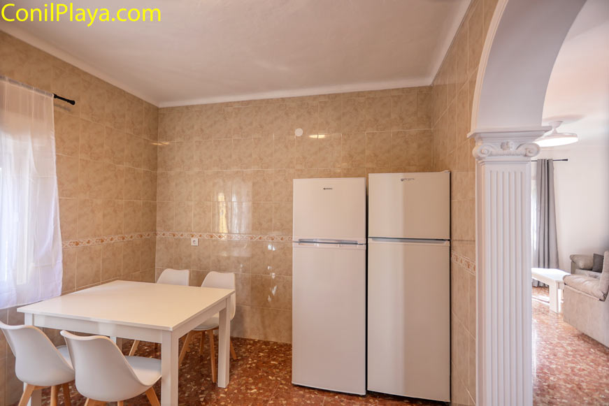 Mesa blanca y dos frigoríficos frente a pared de azulejos beige