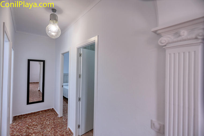 Pasillo luminoso con puertas abiertas y espejo ideal para los preparativos antes de salir