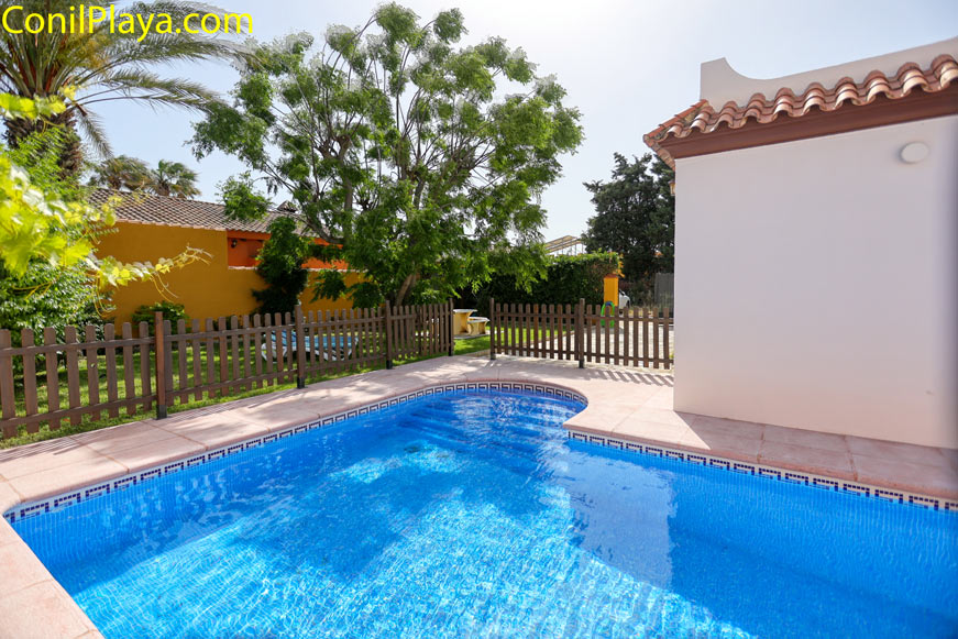 Piscina privada junto a vivienda con jardín y zona vallada visible