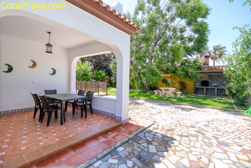 Porche cubierto con mesa de exterior y vistas a jardín con barbacoa