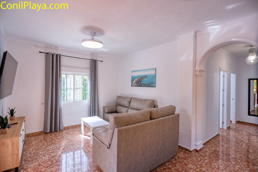 Salón con sofá y ventana junto a pasillo y arcos decorativos