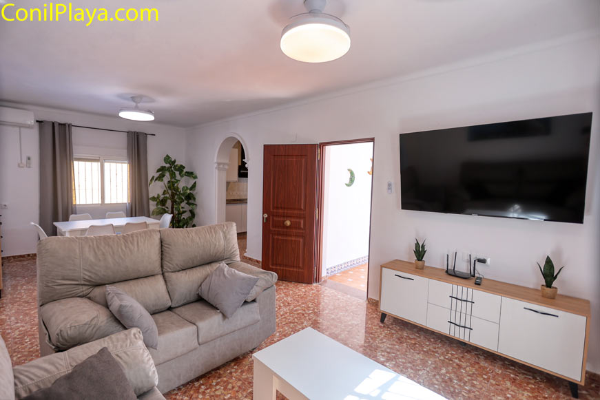 Salón amplio con sofá grande y televisor en la pared principal