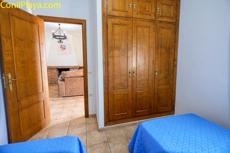 Dormitorio con armario empotrado de madera y camas individuales con colchas azules