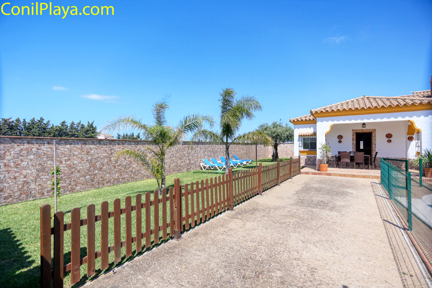 jardín privado con césped y palmeras junto a chalet en alquiler en Conil