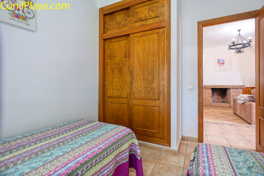 Dormitorio con armario empotrado y vista parcial al salón y chimenea