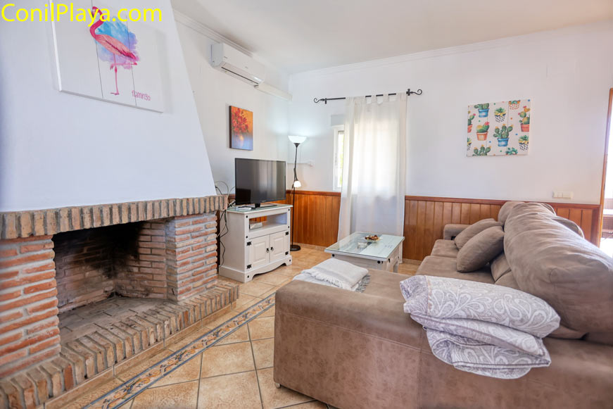 salón luminoso con chimenea, sofá grande y televisión moderna