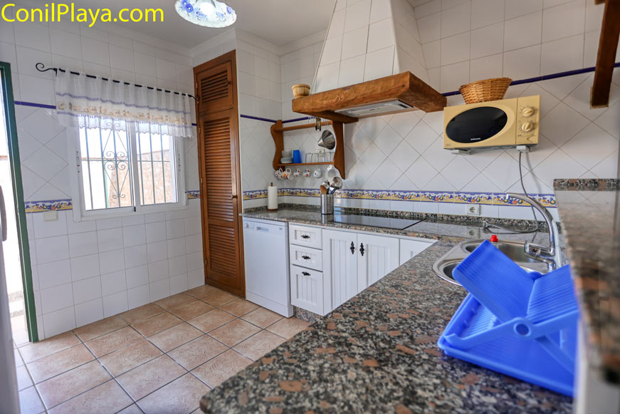 Cocina luminosa con encimera de granito, armarios blancos y microondas antiguo