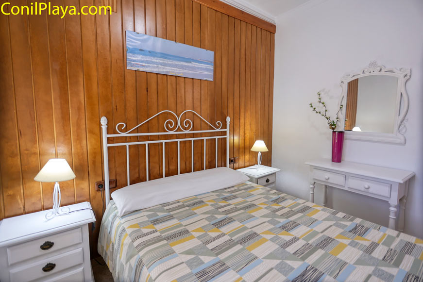 Dormitorio principal con cama de hierro y muebles blancos estilo clásico