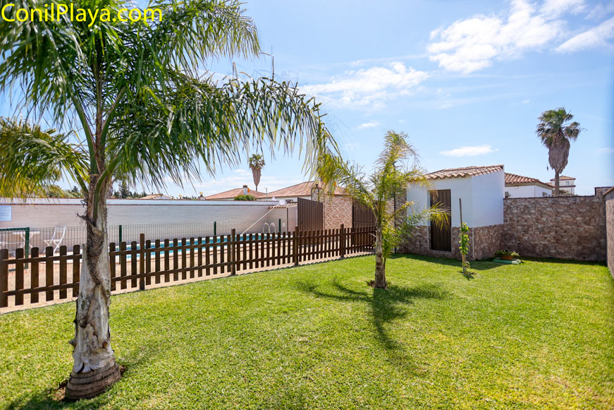 jardin privado con césped y varias palmeras junto a una pequeña caseta
