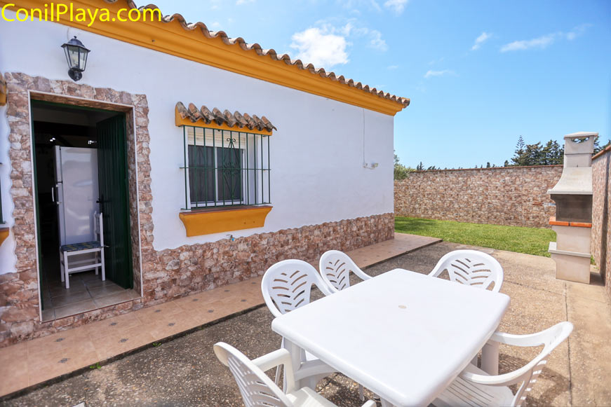 mesa de jardín con sillas y barbacoa junto a casa de piedra