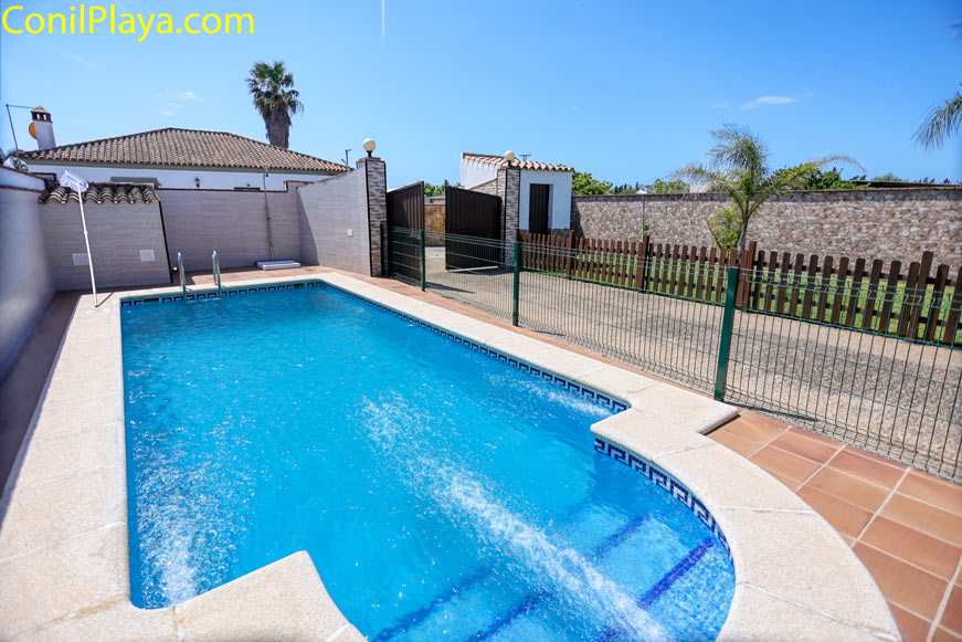 Piscina privada vallada junto a chalet con espacio para tomar el sol