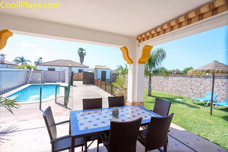 porche con mesa bajo toldo junto a piscina y jardín privado