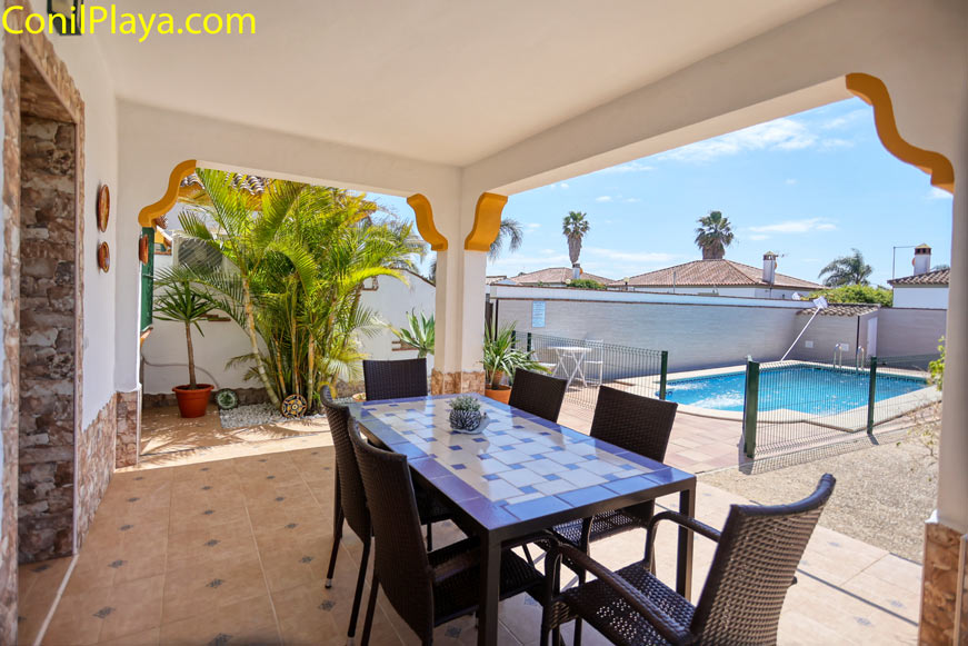 porche cubierto con mesa y sillas junto a piscina privada y plantas decorativas