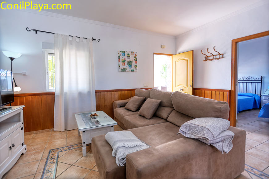 salón luminoso con sofá chaiselongue, mesa de centro y acceso a dormitorio