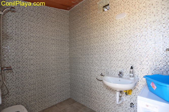 Cuarto de baño con lavabo pequeño y ducha visto desde la entrada
