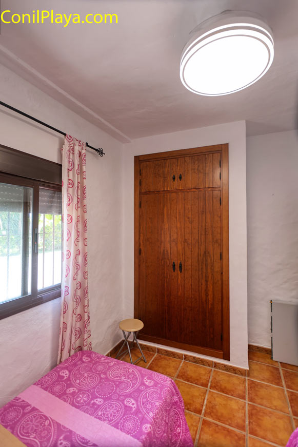 Dormitorio pequeño con armario empotrado, ventana y cama individual visible