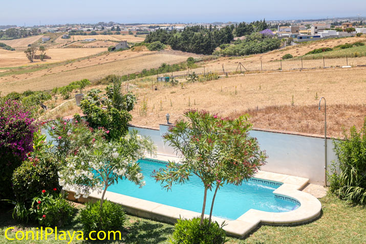 Piscina privada rodeada de jardín y vistas al campo desde la azotea, al fondo está Conil