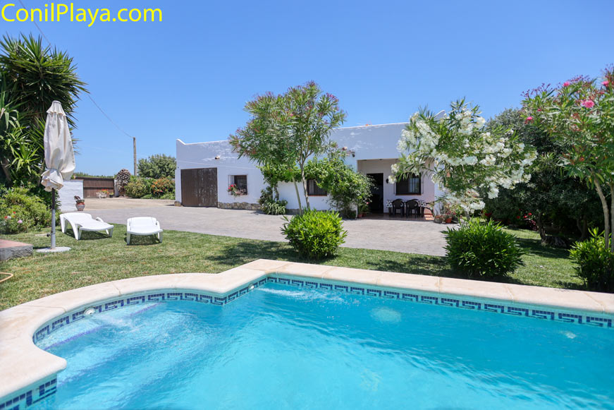 Vista desde la piscina al jardín y fachada de la casa en Conil