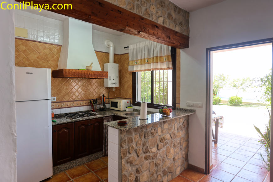 Cocina rústica con barra de piedra y salida directa al jardín