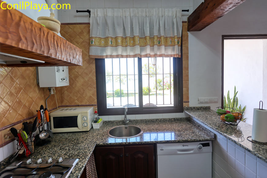 Cocina luminosa con ventana, encimera de granito y lavavajillas
