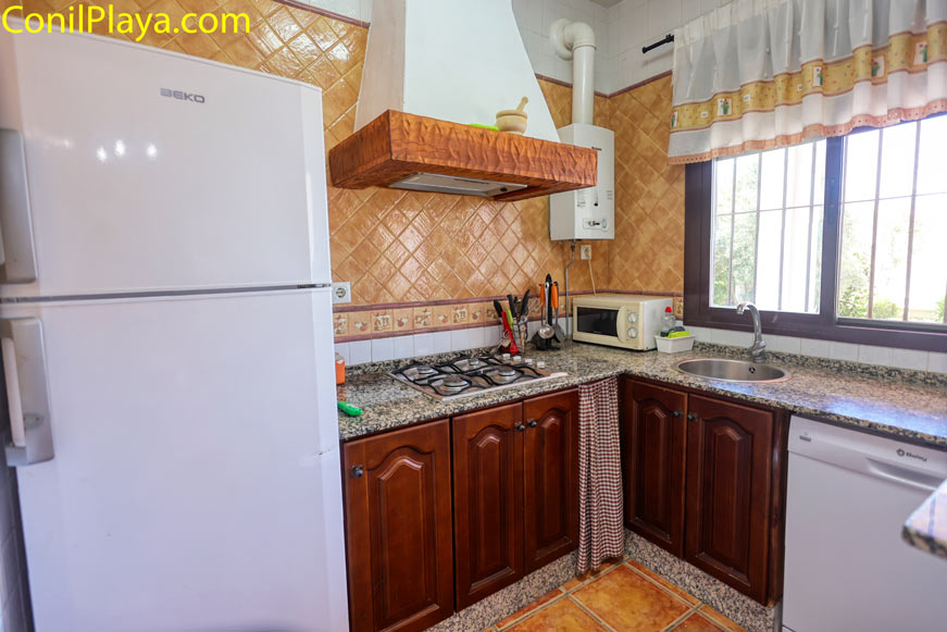 Cocina moderna con nevera, lavavajillas, microondas, fregadero y armarios blancos.