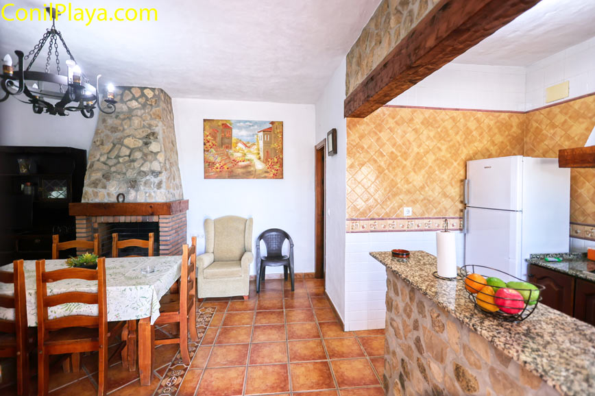 Comedor rústico con chimenea, mesa de madera y cocina integrada visible