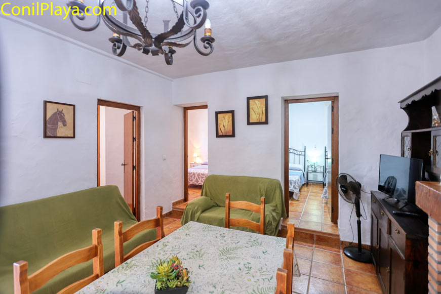 Comedor con mesa y sillas de madera junto a salón y dos dormitorios