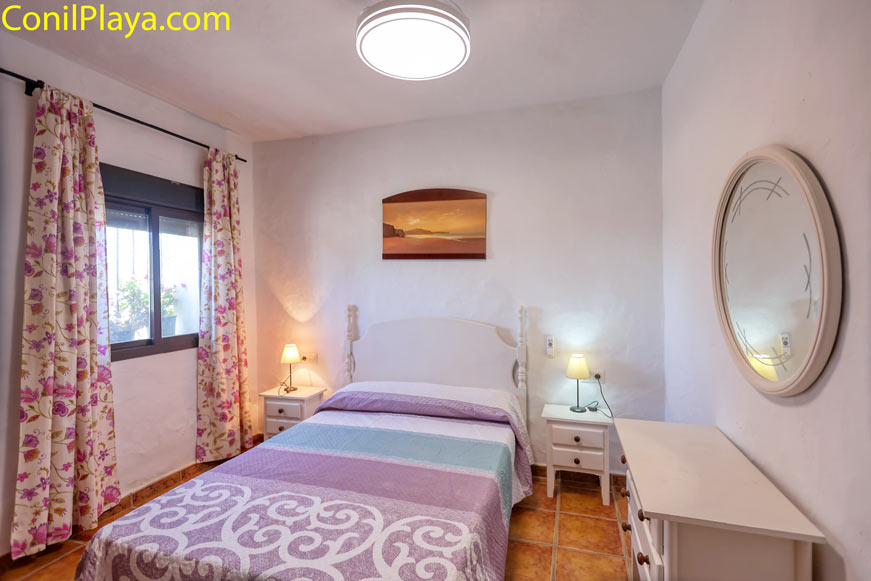 Dormitorio principal con cama doble y muebles sencillos junto a ventana