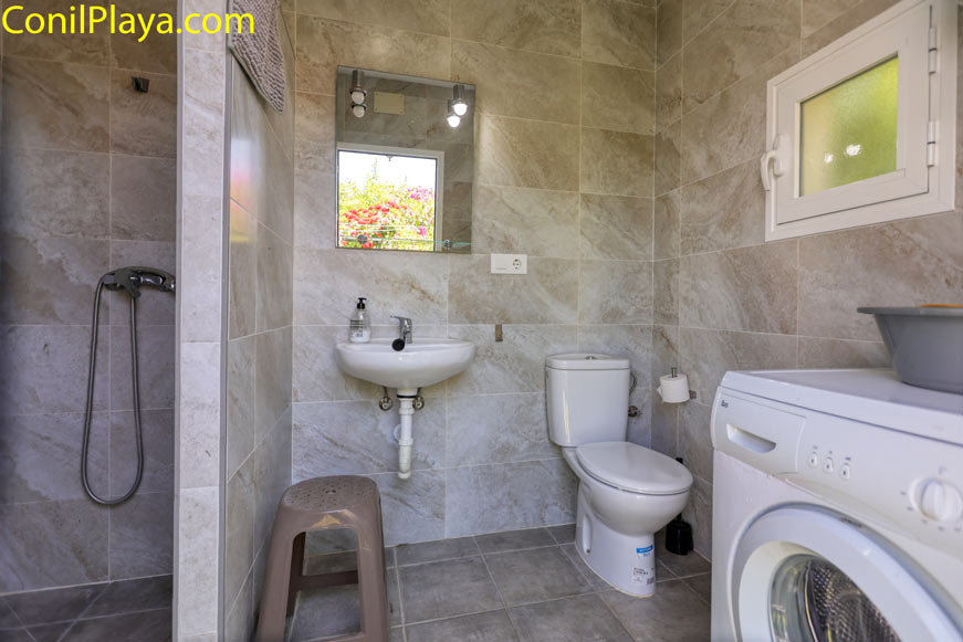 Cuarto de baño con ducha, lavabo, inodoro y lavadora desde la puerta