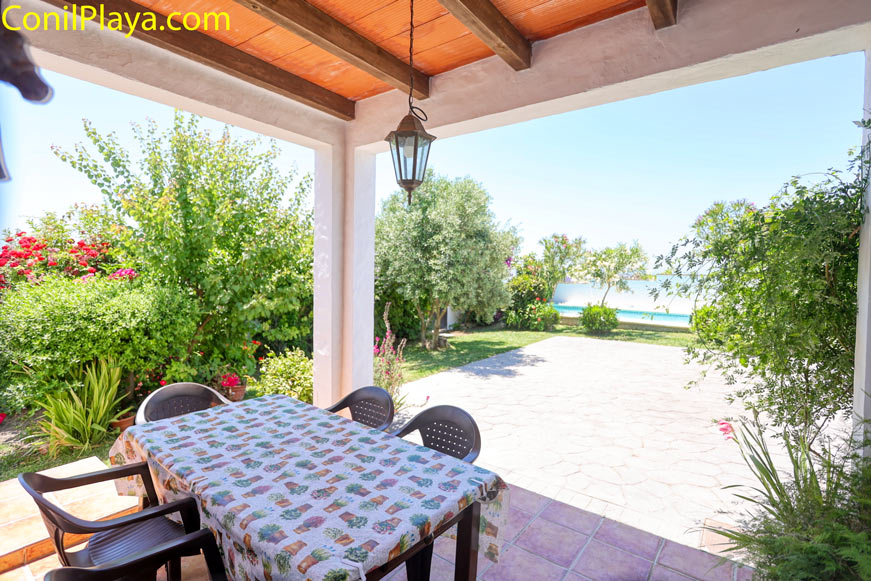 Mesa en el porche con vistas al jardín y piscina privada de la vivienda